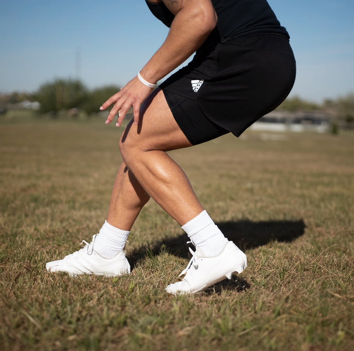 Bread Cloud White elastic shoelace threaded through sports cleats, showing flexible and durable athletic shoe laces for sneakers.