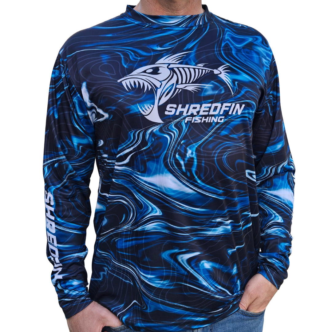 ShredFin StormSurge Performance Shirt in Blue Abyss, lightweight and breathable, displayed on a hanger in a modern minimalist living room.
