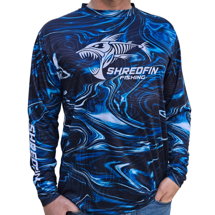 ShredFin StormSurge Performance Shirt in Blue Abyss, lightweight and breathable, displayed on a hanger in a modern minimalist living room.
