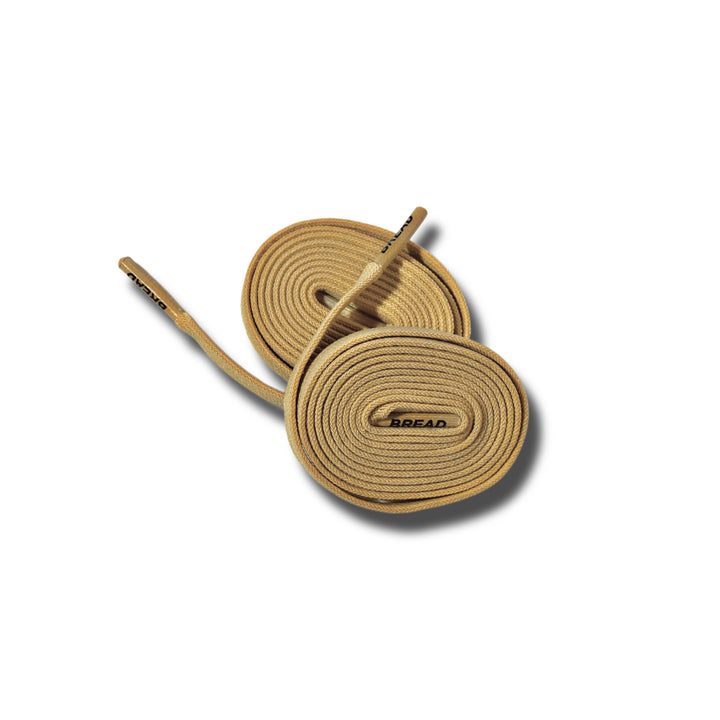 Desert tan elastic shoelace by Bread, showing close-up of flexible, durable laces with metal aglets on a plain background.