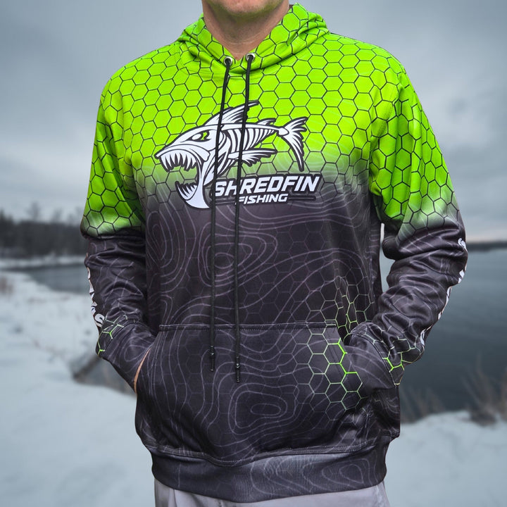 ShredFin HexCast Elite performance hoodie in chartreuse and black fade, shown in an outdoor setting after lake fishing.
