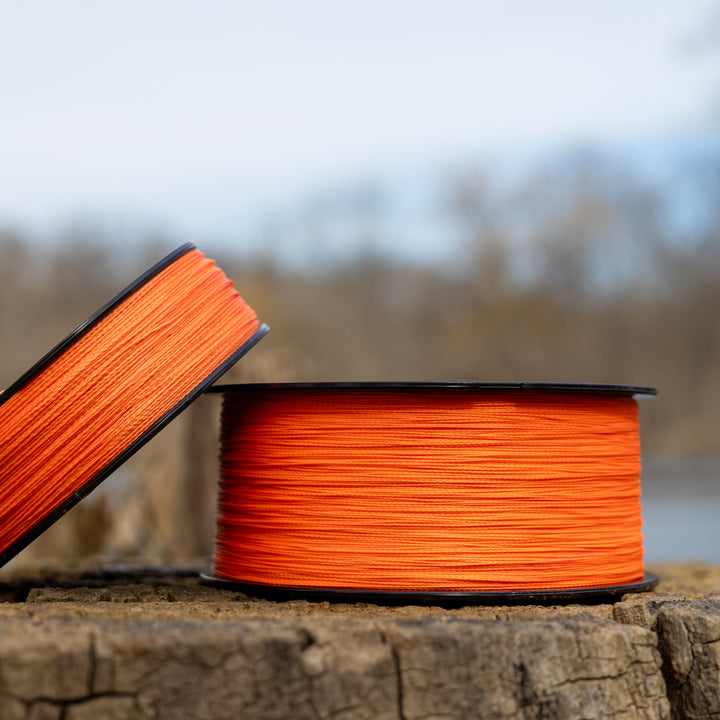 Reaction Tackle braided fishing line in high-visibility orange, showcasing its durable, thin braided design for fishing.