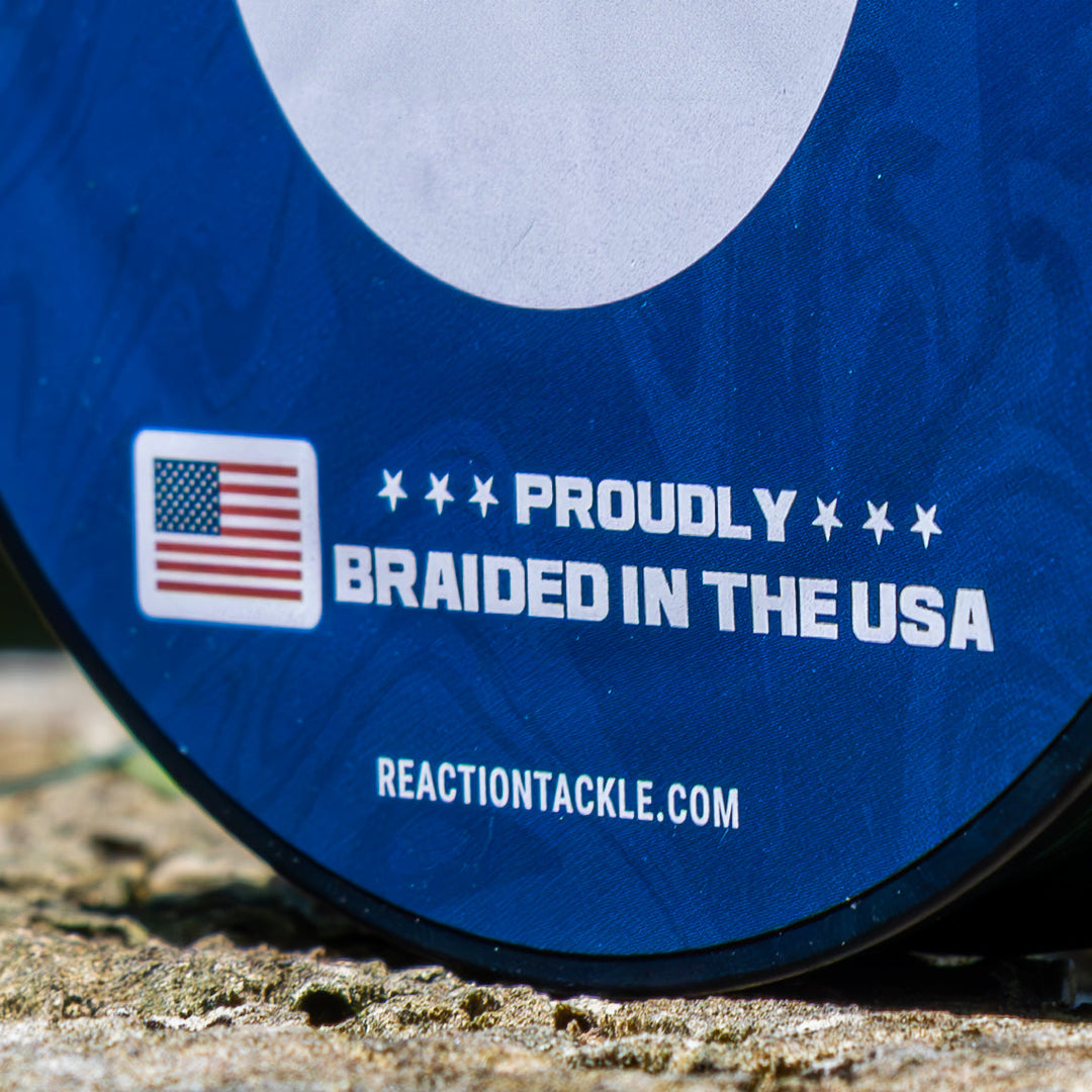 Reaction Tackle braided fishing line, USA-made, shown coiled on spool with detailed labeling and vibrant packaging.