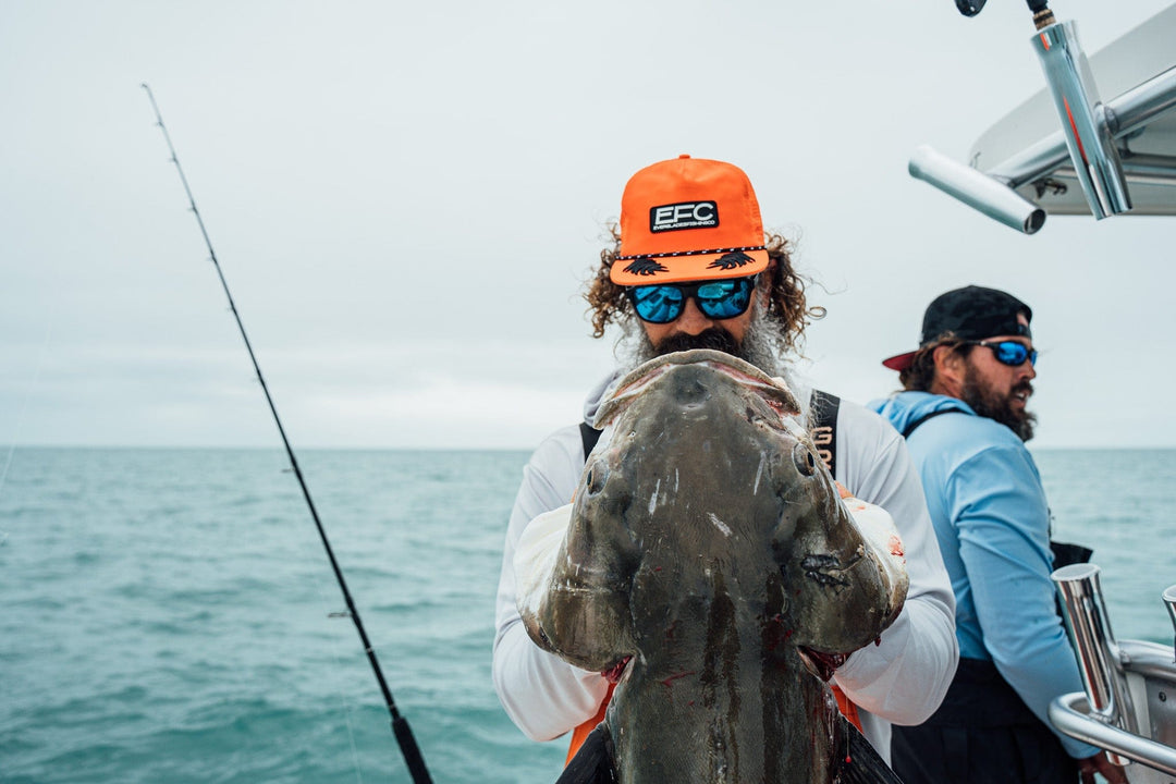 Man wearing a black Everglades Fishing Co. Late Night Snapback cap with adjustable strap and embroidered logo.