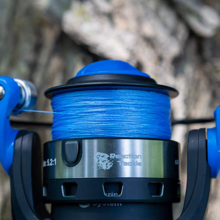 Reaction Tackle braided fishing line, 5X USA-made, shown coiled on spool with detailed labeling and vibrant packaging.