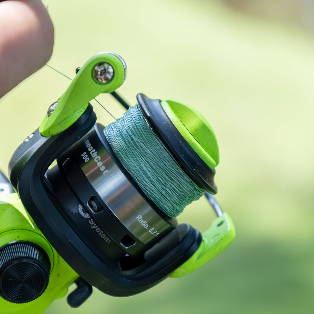 Reaction Tackle braided fishing line, 5X strength, made in the USA, shown coiled with a fishing rod and reel in the background.