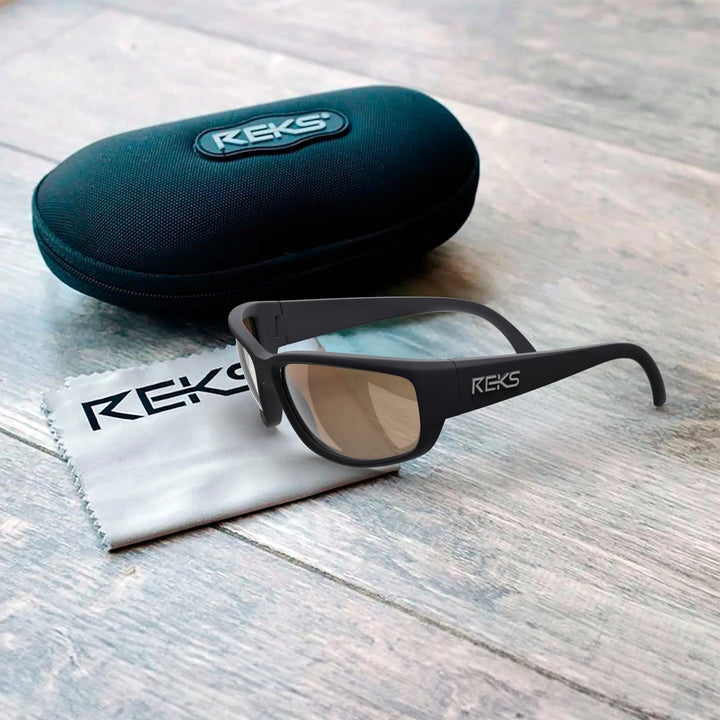 Large REKS® wrap prescription polarized polycarbonate sunglasses with black frame and dark lenses, displayed in a protective case.