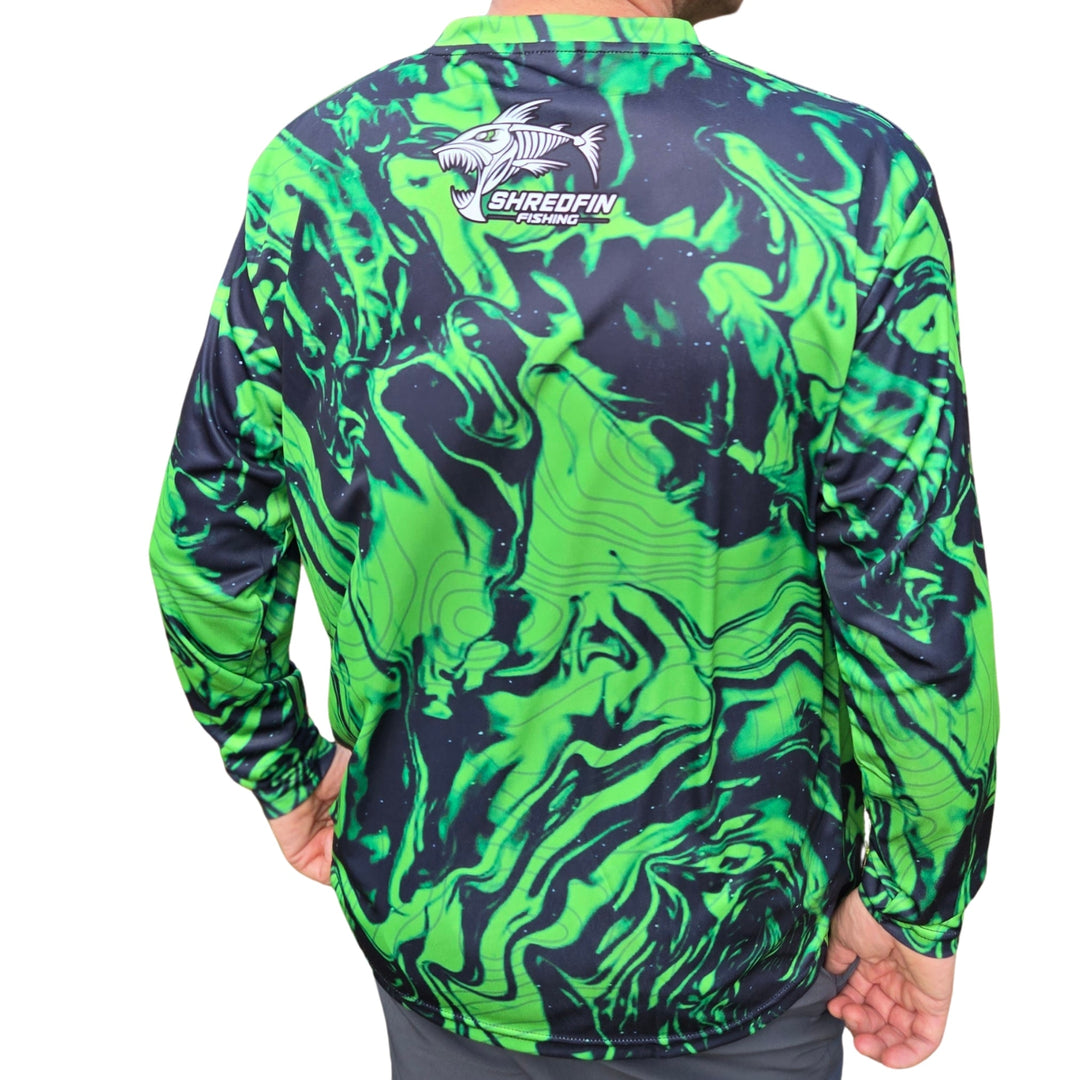 ShredFin StormSurge Performance Shirt in Toxic Lime Swirl displayed in a minimalist living room setting.