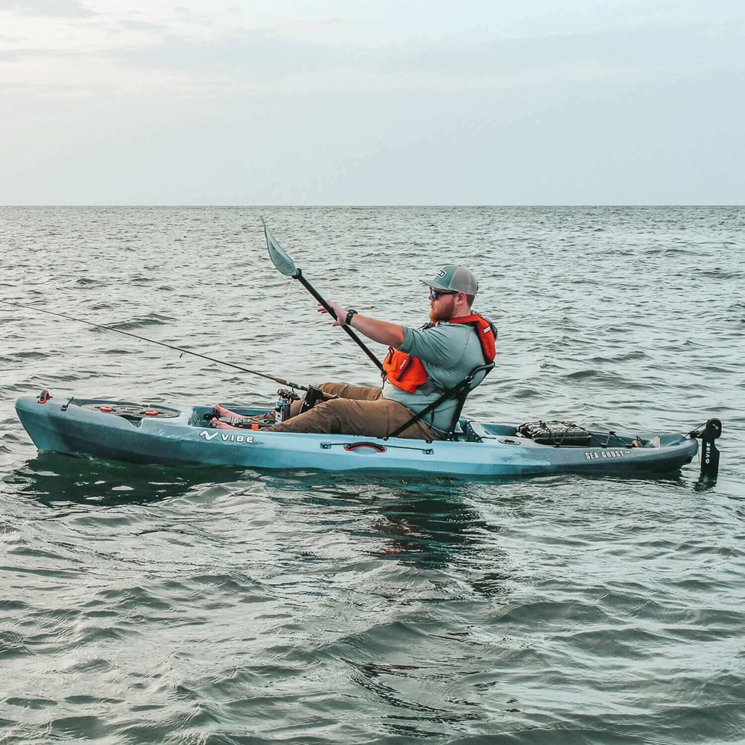 Vibe Kayaks Sea Ghost 110 kayak in blue with adjustable seat, paddle, and storage compartments on calm water.